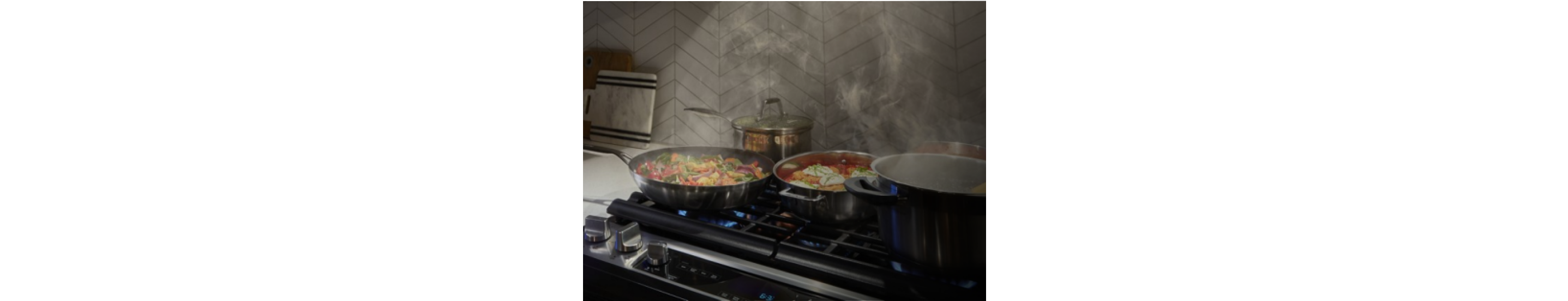 Multiple pans with food cooking in them on a gas cooktop