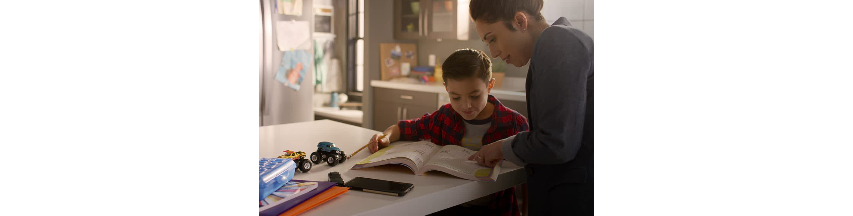 Woman helping a child with homework at a kitchen island