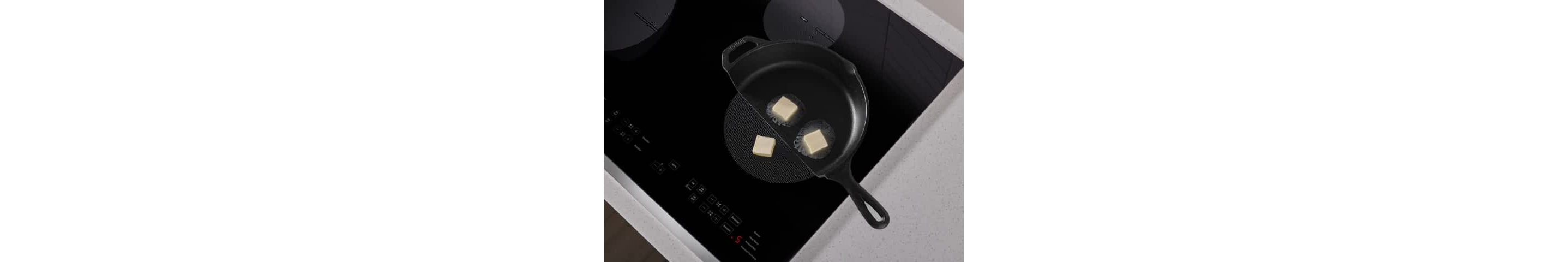 A frying pan cut in half on an induction cooktop, showing butter melting in the pan and not melting on the exposed element.