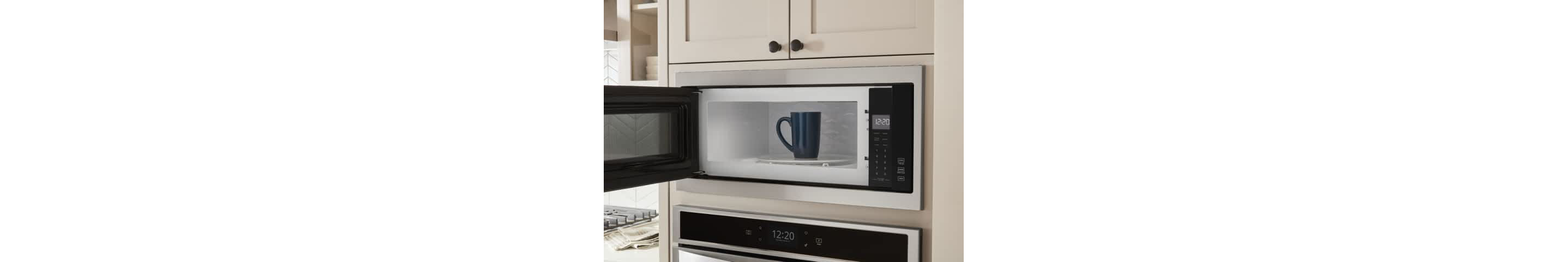 A coffee cup sits inside an open Whirlpool® Microwave