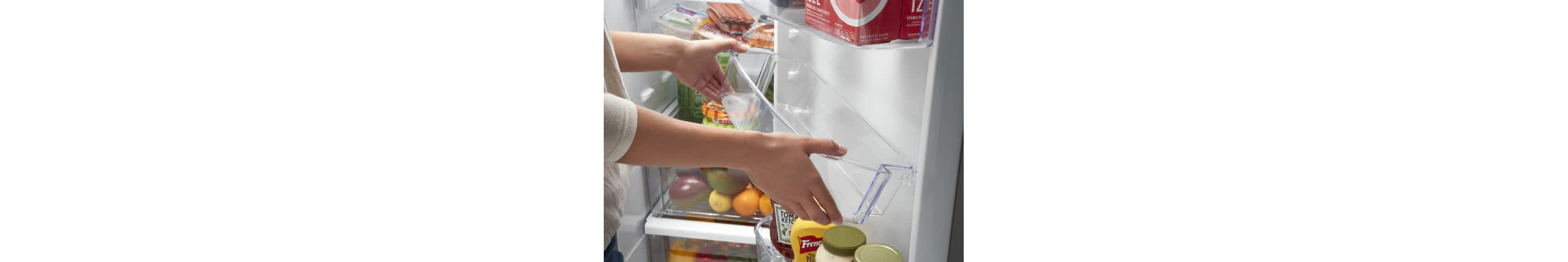 A woman moves the Adjustable Gallon Door Bin in a Whirlpool® Refrigerator