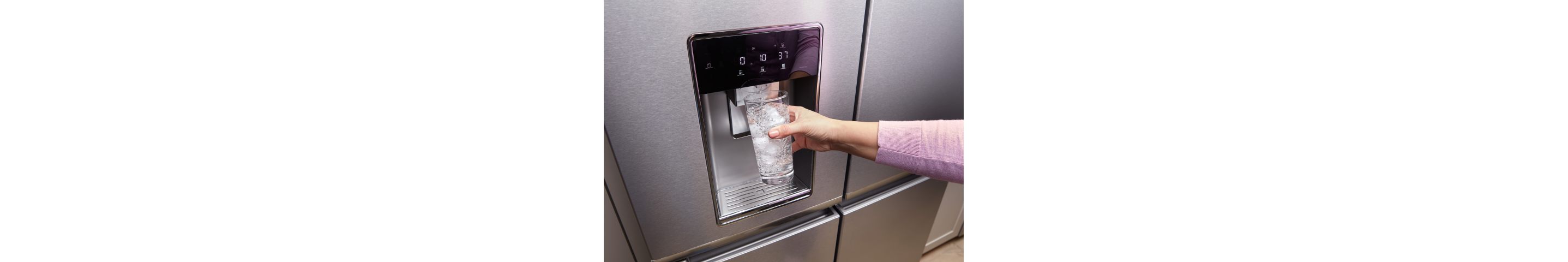A hand getting water from the fridge dispenser