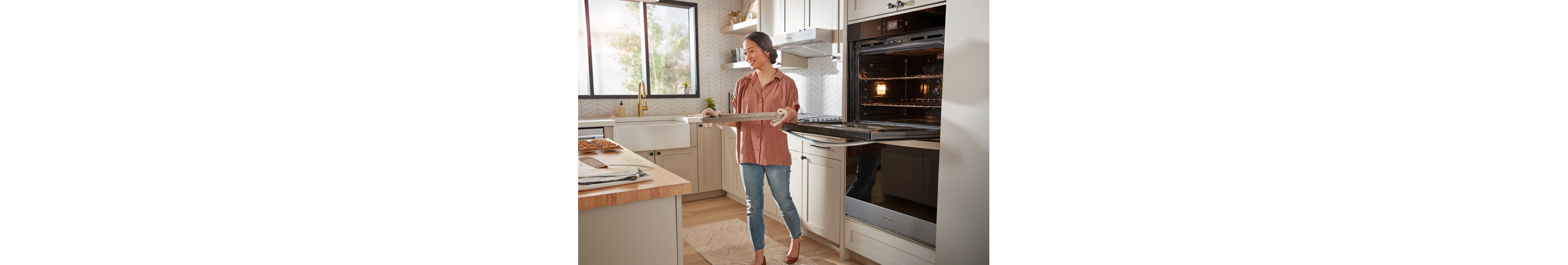 A person removing a tray of food from a Whirlpool® Wall Oven