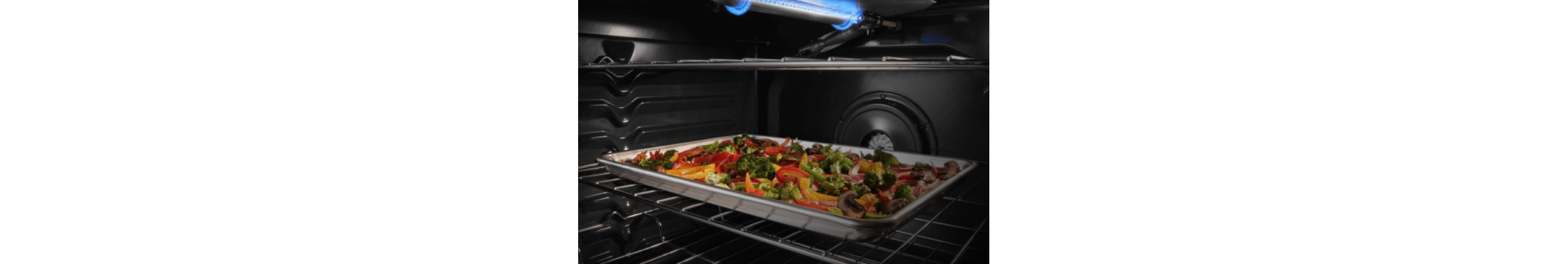 A sheet pan with vegetables inside an oven