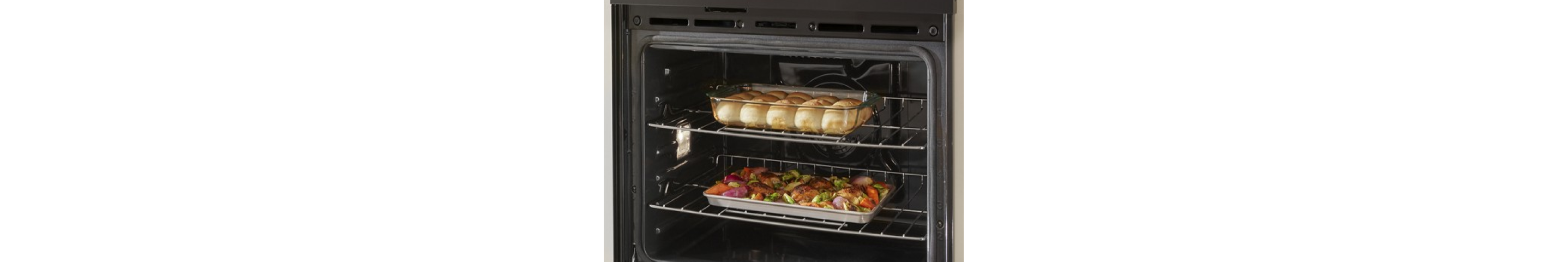 Rolls and a sheet pan dinner on different racks in a wall oven