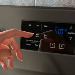 A person operating the control panel of their oven