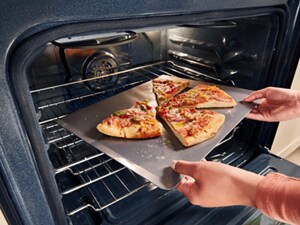 Someone pulling a pan of pizza out of an oven
