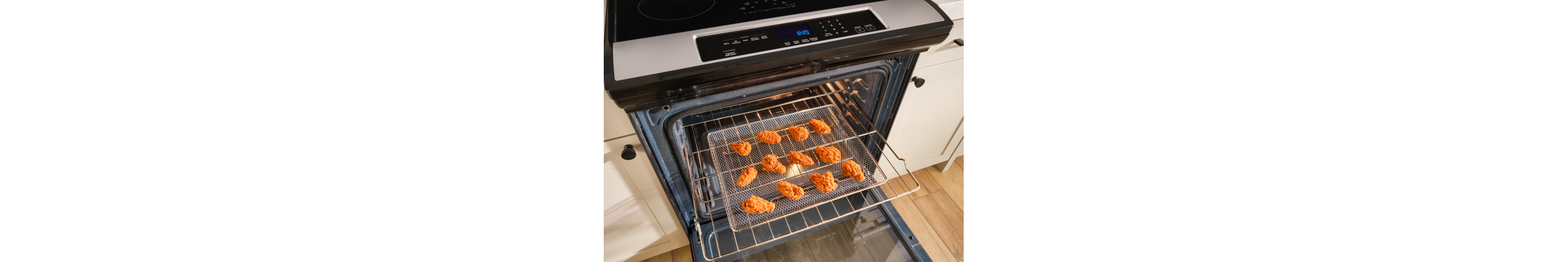 A basket of chicken wings being air fryed in an oven
