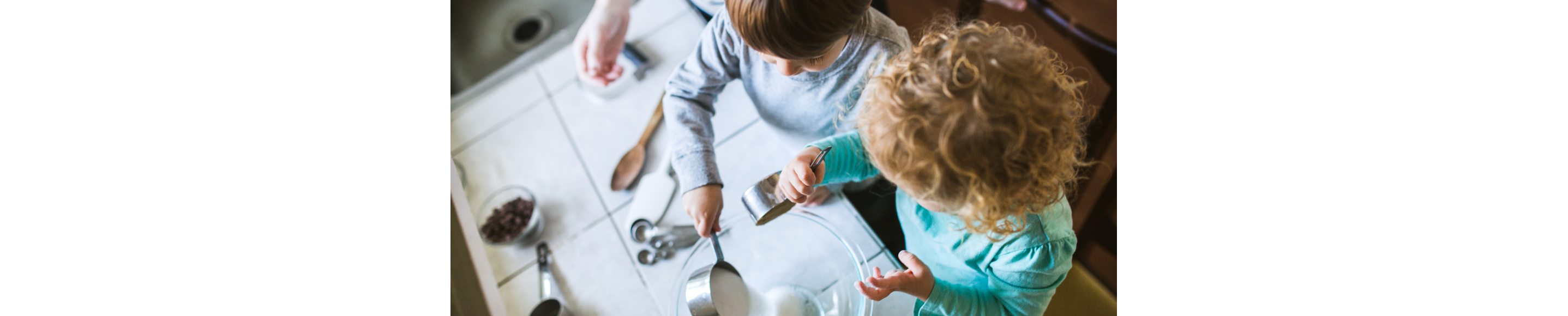 Two kids helping mix ingredients in the kitchen