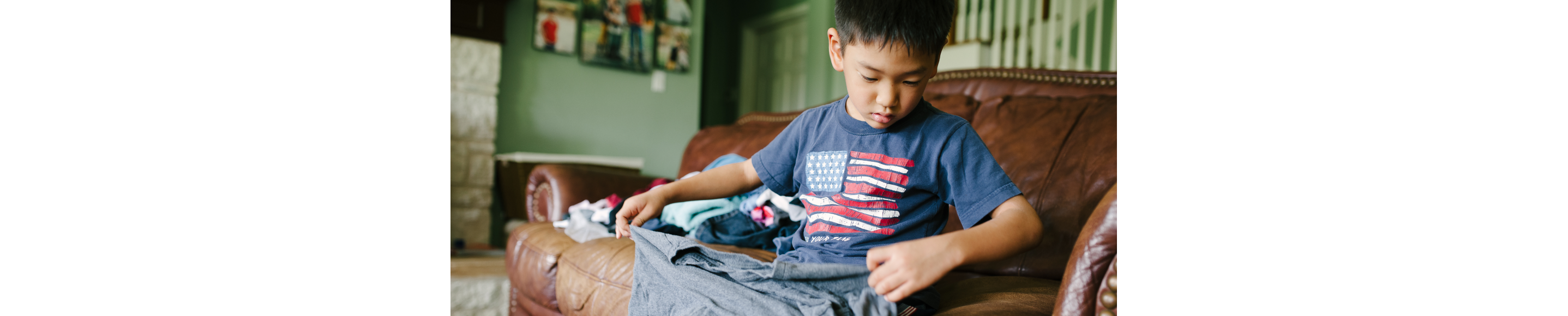 Young child helping fold laundry on the couch