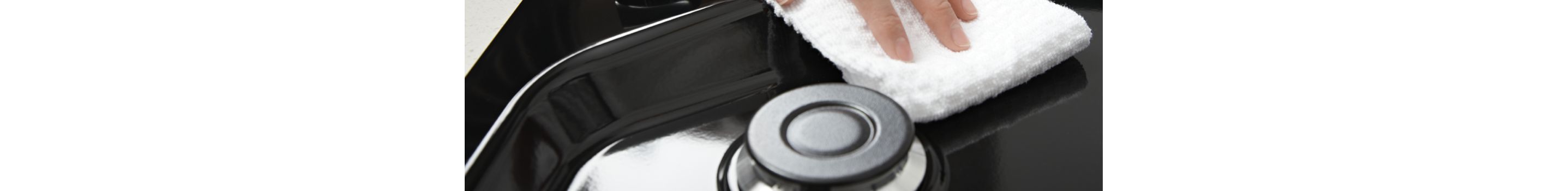 Hands wiping down the top of a Whirlpool® Gas Cooktop