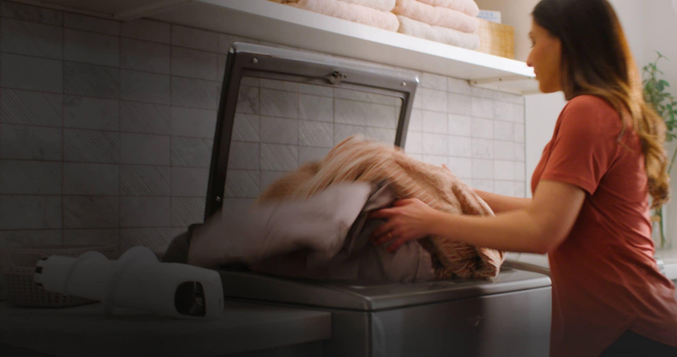 Woman loading laundry into a washer featuring the 2 in 1 Removable Agitator
