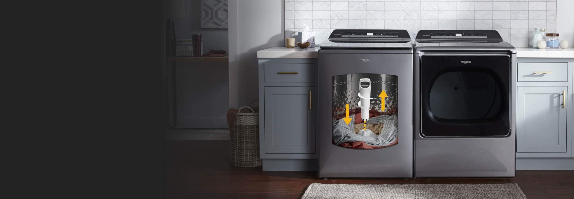 In a laundry room with grey cabinets are a Whirlpool Top Load Washing Machine and a Whirlpool Front Load Dryer