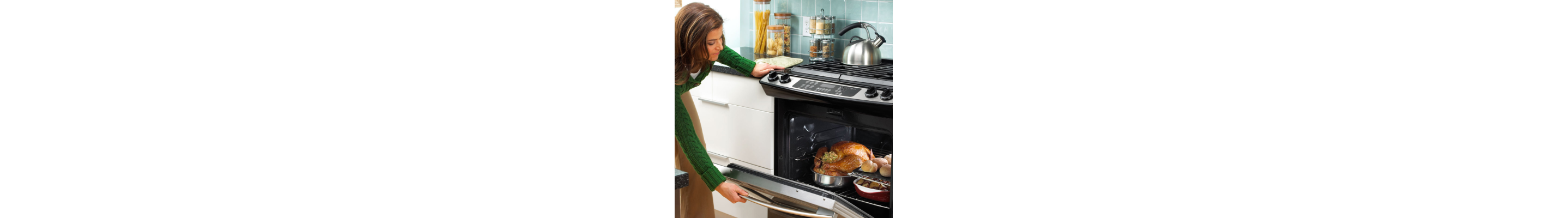 Woman closing door of oven filled with chicken, bread and other foods