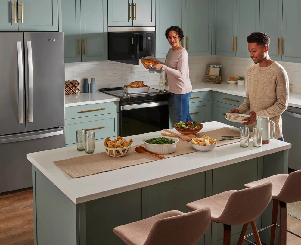 People preparing food in a modern kitchen with Whirlpool® Appliances
