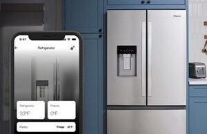 A smart phone with the Whirlpool App on it in front of a refrigerator's water dispenser.