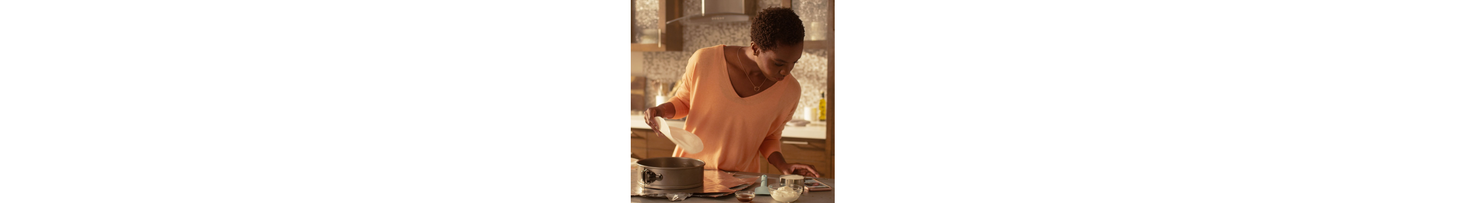Person reviewing recipe on phone while preparing a springform pan