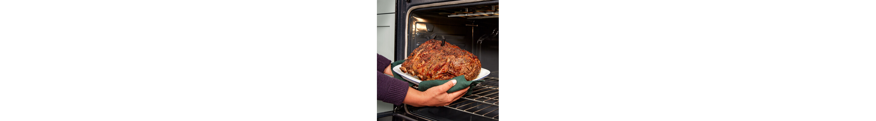 Person removing oven-roasted meat from the oven