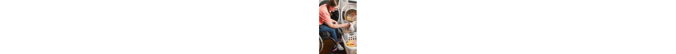 Person in a wheelchair loading laundry in a front load washer