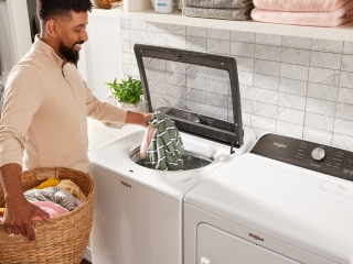 Person loading laundry in a top load washer