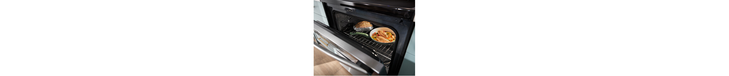 An oven door ajar exposing two dishes cooking inside
