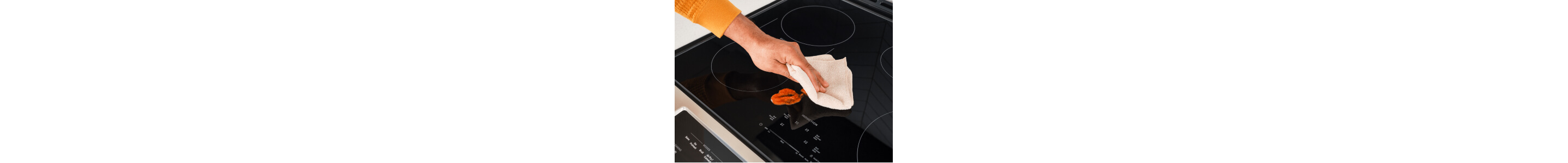 A hand cleaning up a spill on an induction cooktop