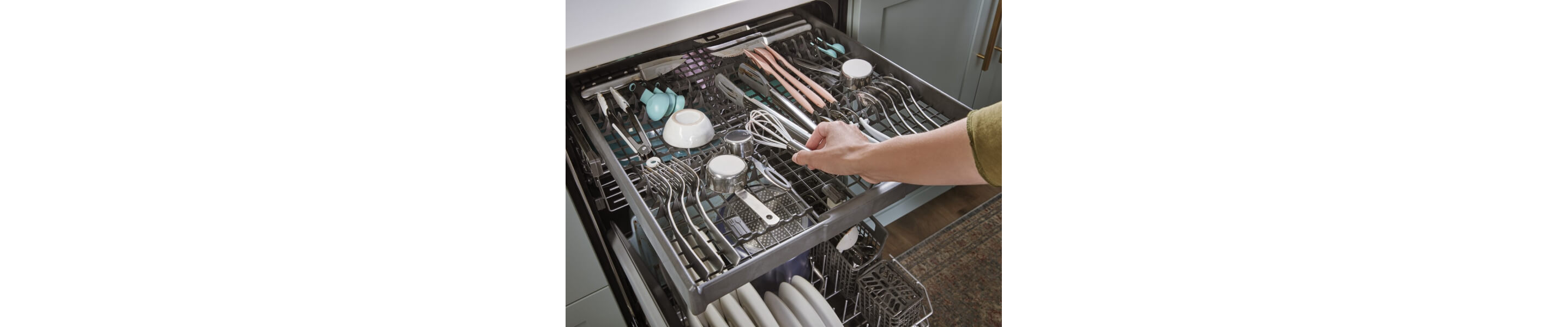 Person placing a whisk on a third-level dishwasher rack