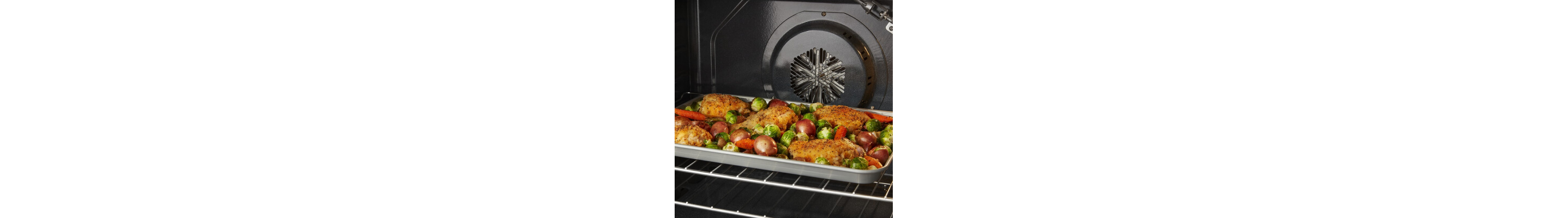 Chicken and vegetables on a baking sheet inside an oven