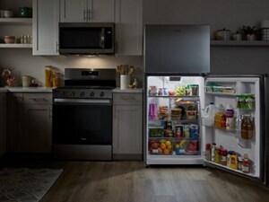 Top freezer refrigerator with refrigerator door open and stocked with food