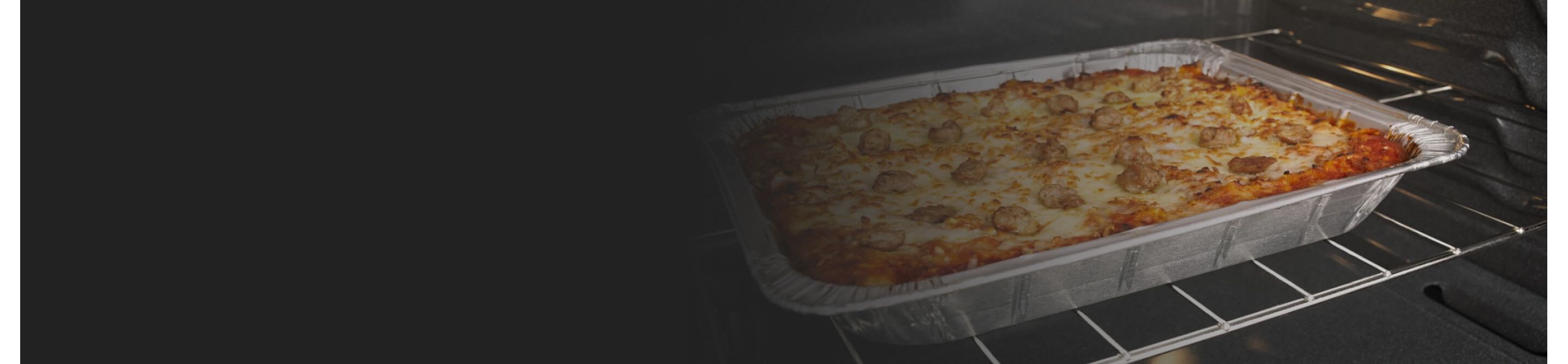 Lasagna cooking in a foil pan in the oven
