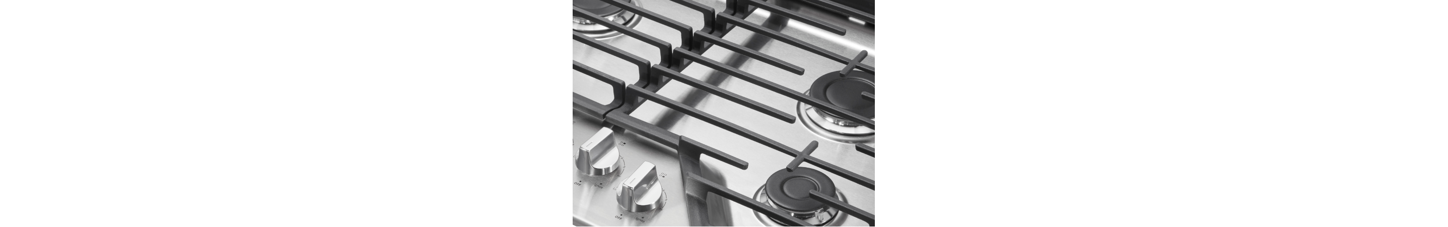 Closeup of stainless steel cooktop knobs, burners, and grates