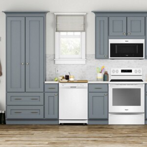 A white dishwasher in a modern grey cabinet kitchen located near dish and utensil storage