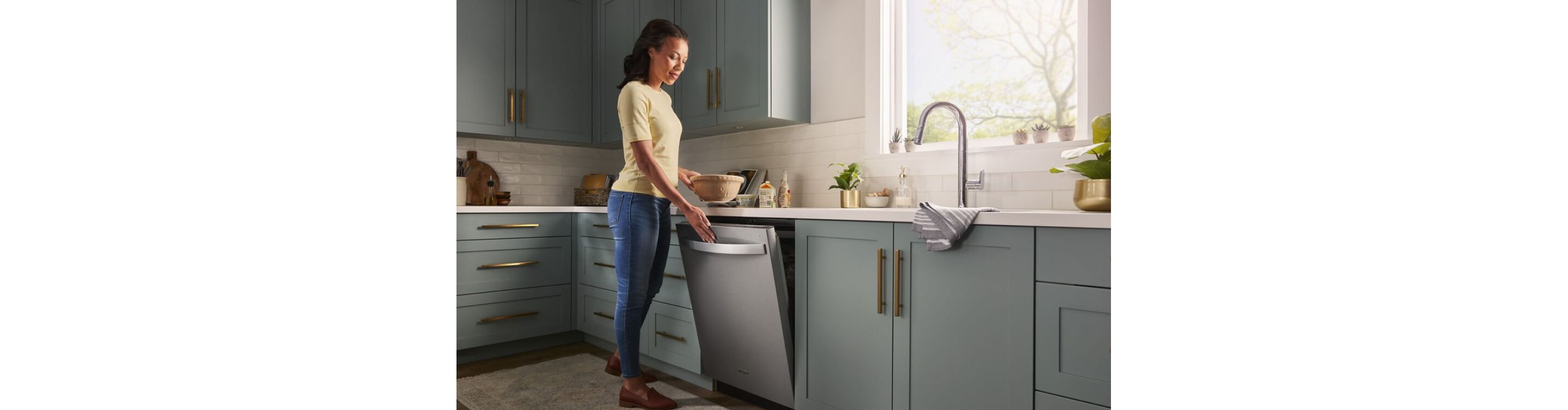 A person opening a dishwasher in a kitchen