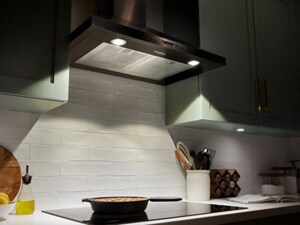 Range hood with light on between green cabinets