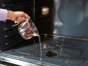 Person pouring water into an oven with no racks