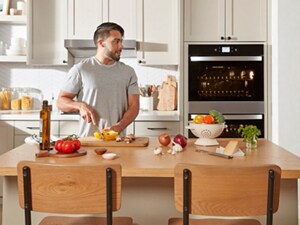 Person prepping veggies on an island in front of a Whirlpool® Double Wall Oven
