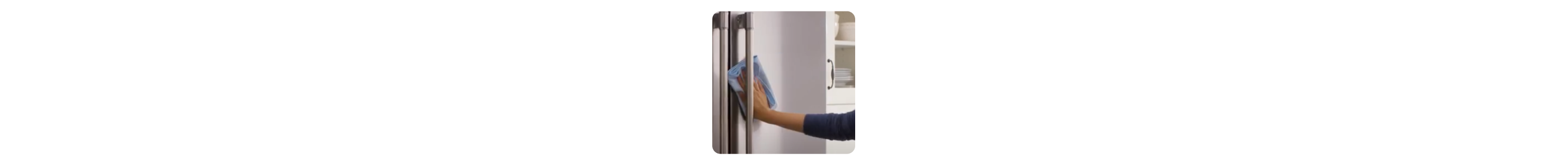 Hand wiping a stainless steel refrigerator with a dry cloth