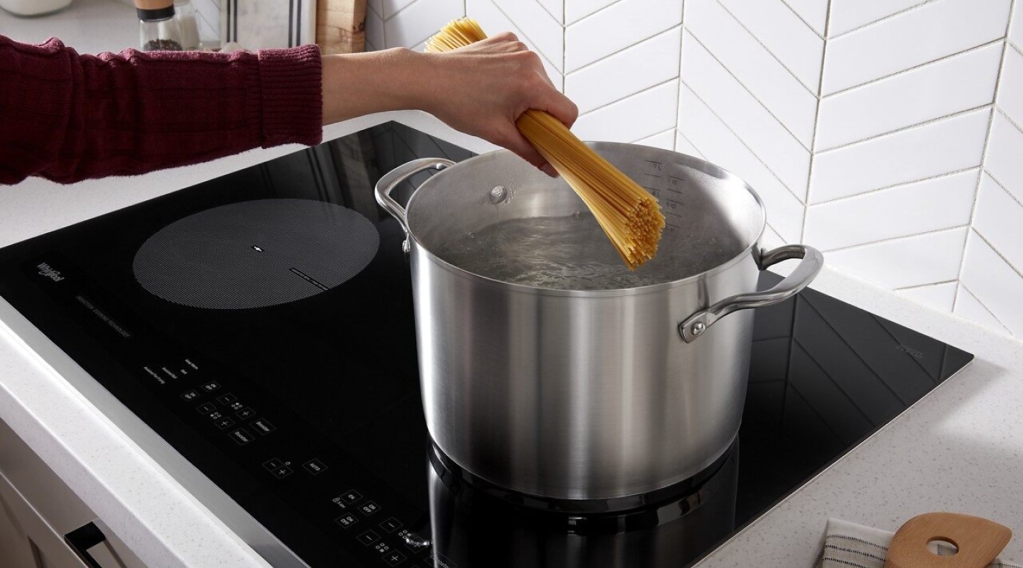 Person adding spaghetti to boiling water