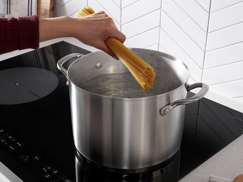 Person adding spaghetti to boiling water