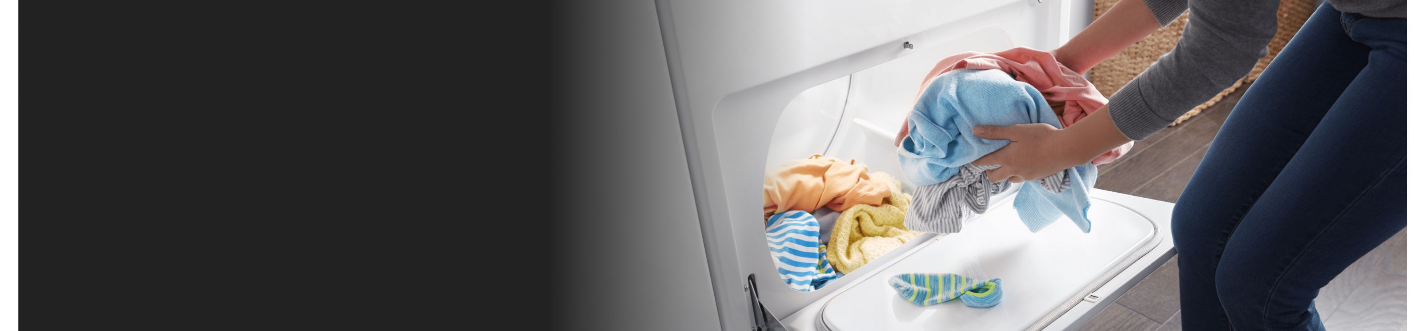 A person taking colorful clothes out of a dryer.