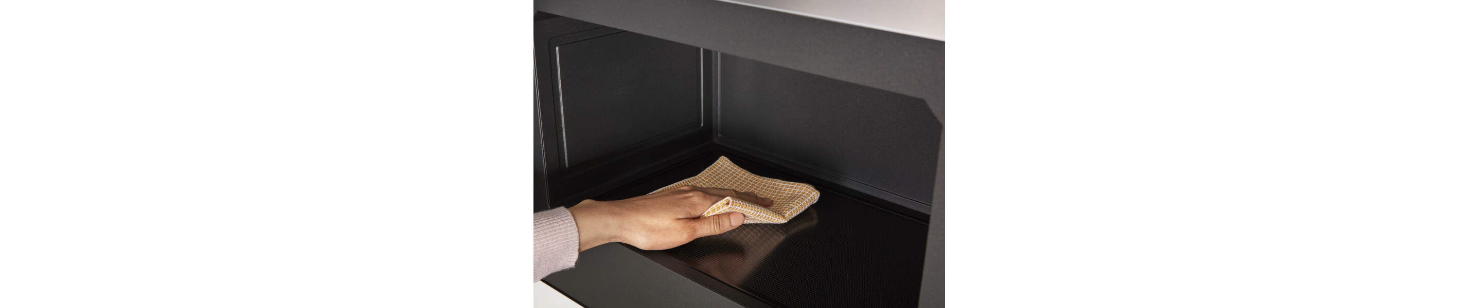 Person wiping the inside of the microwave