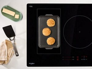 An overhead view of an induction cooktop with pancakes on the griddle