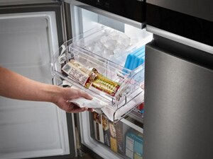 A person pulling out a freezer drawer that contains ice