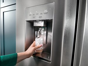 A person filling a glass with ice at a refrigerator’s external ice and water dispenser