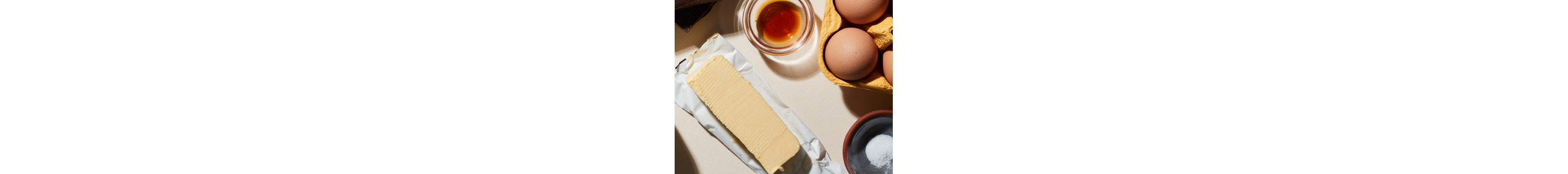 Open stick of butter next to cooking oil, eggs and seasoning