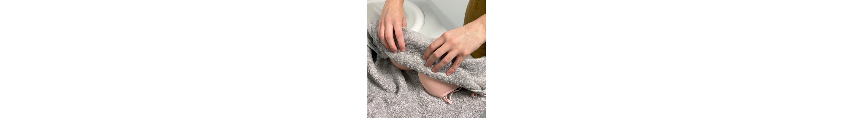 Person squeezing out excess water from a bra with a towel