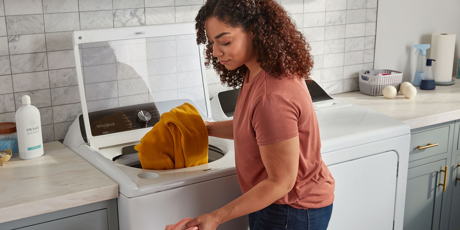 Woman loading clothes into white WhirlpoolÂŽ top load washer