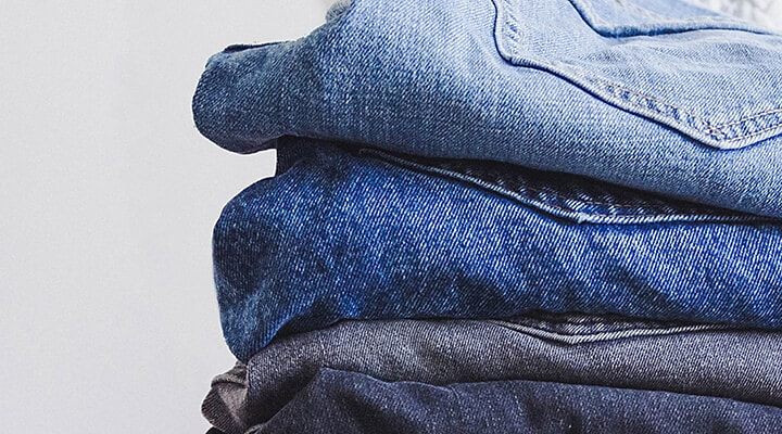 Four pairs of folded blue jeans
