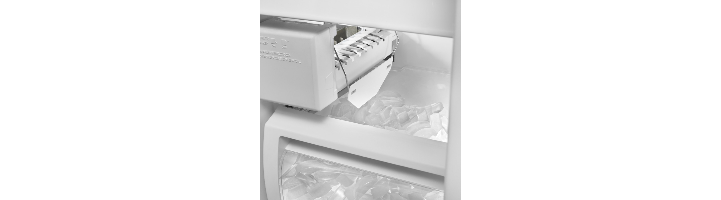 Close-up of ice maker dispenser arm above full bin of ice