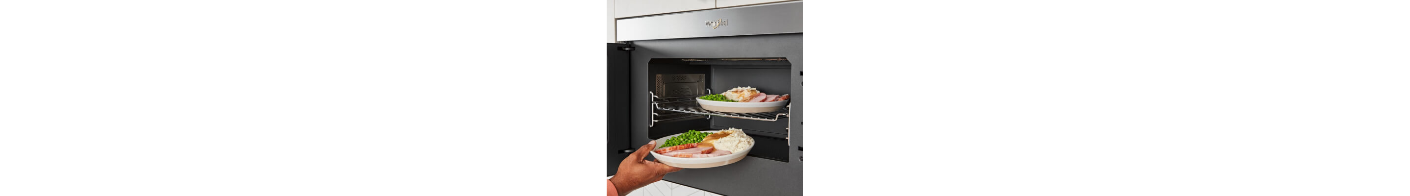 Person loading multiple dishes into and under cooking rack in microwave